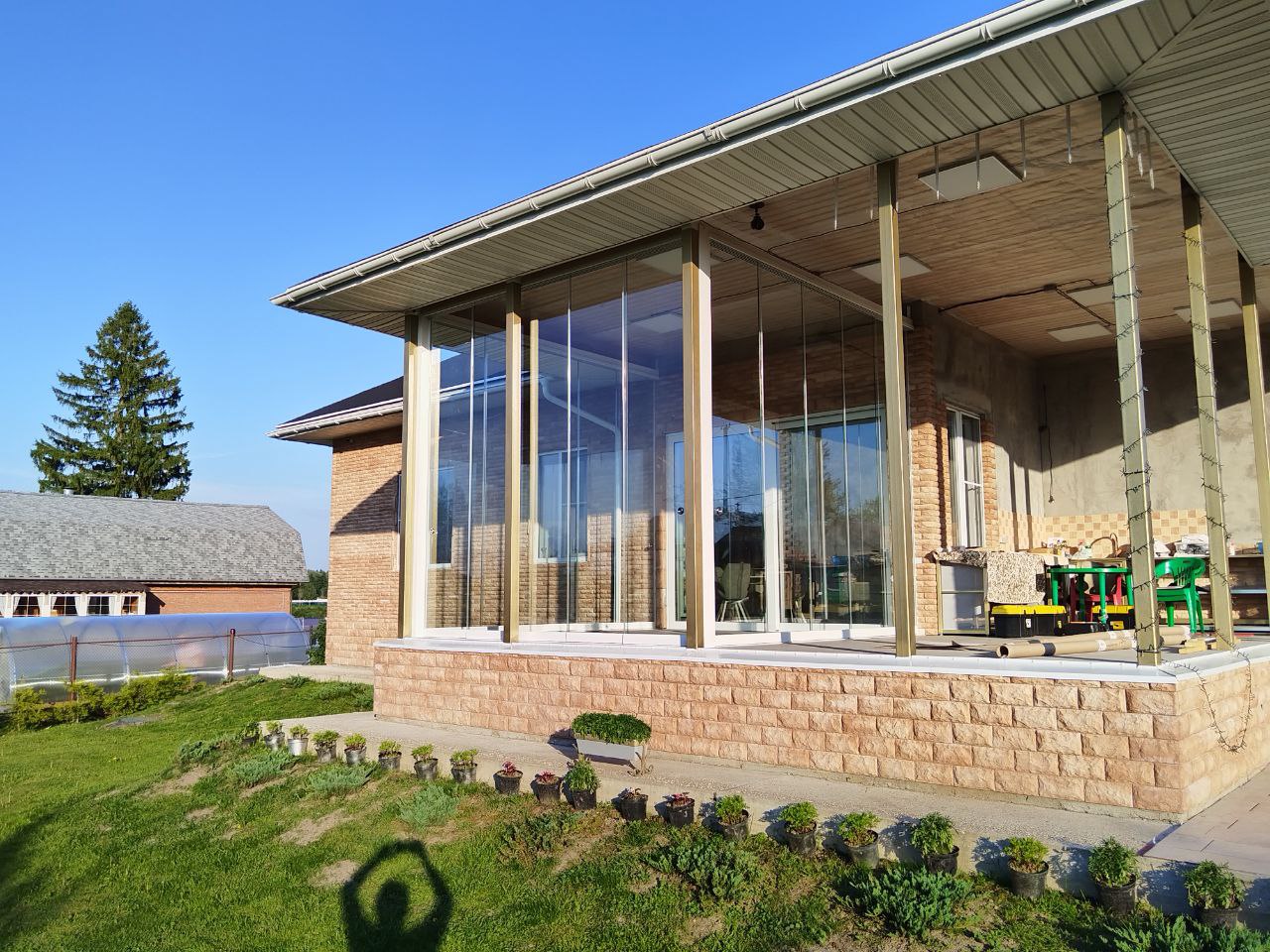 Закрытая веранда с безрамным остеклением, деревянными балками и видом на сад